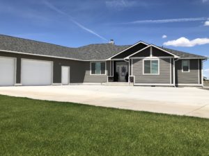Adult Family Center of Moses Lake: Affordable senior care facility in Washington State featuring a modern gray ranch-style house with memory care housing and a manicured lawn for elderly residents.